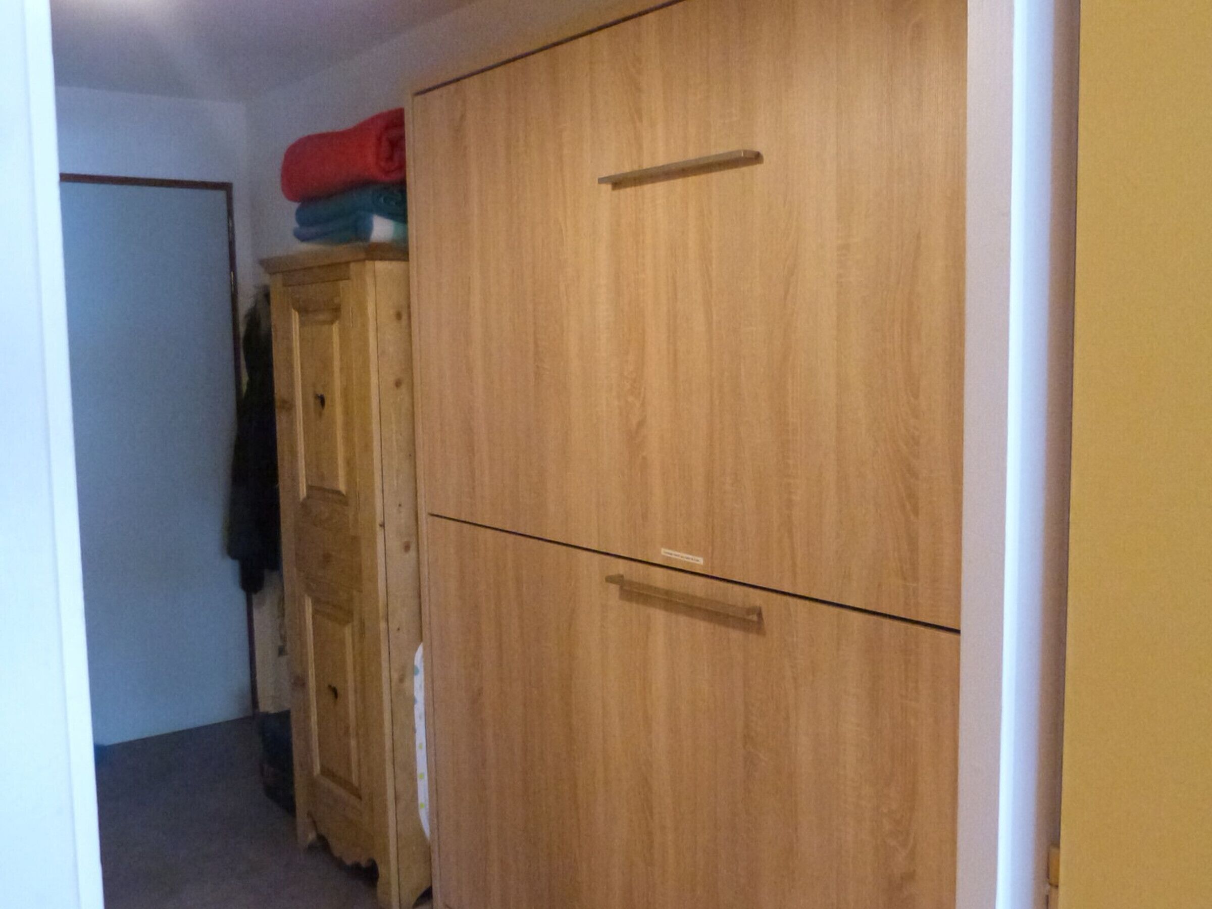 Ein Holzschrank mit zwei Türen und Griff, eine kleine Holzkabine und ein rotes Objekt darauf.