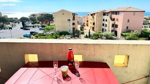 A balcony with a table set for two, a bottle of red drink, and a glass of water. - Cosy T2 sea view, bedroom + cabin, mezzanine, parking (Fleury)