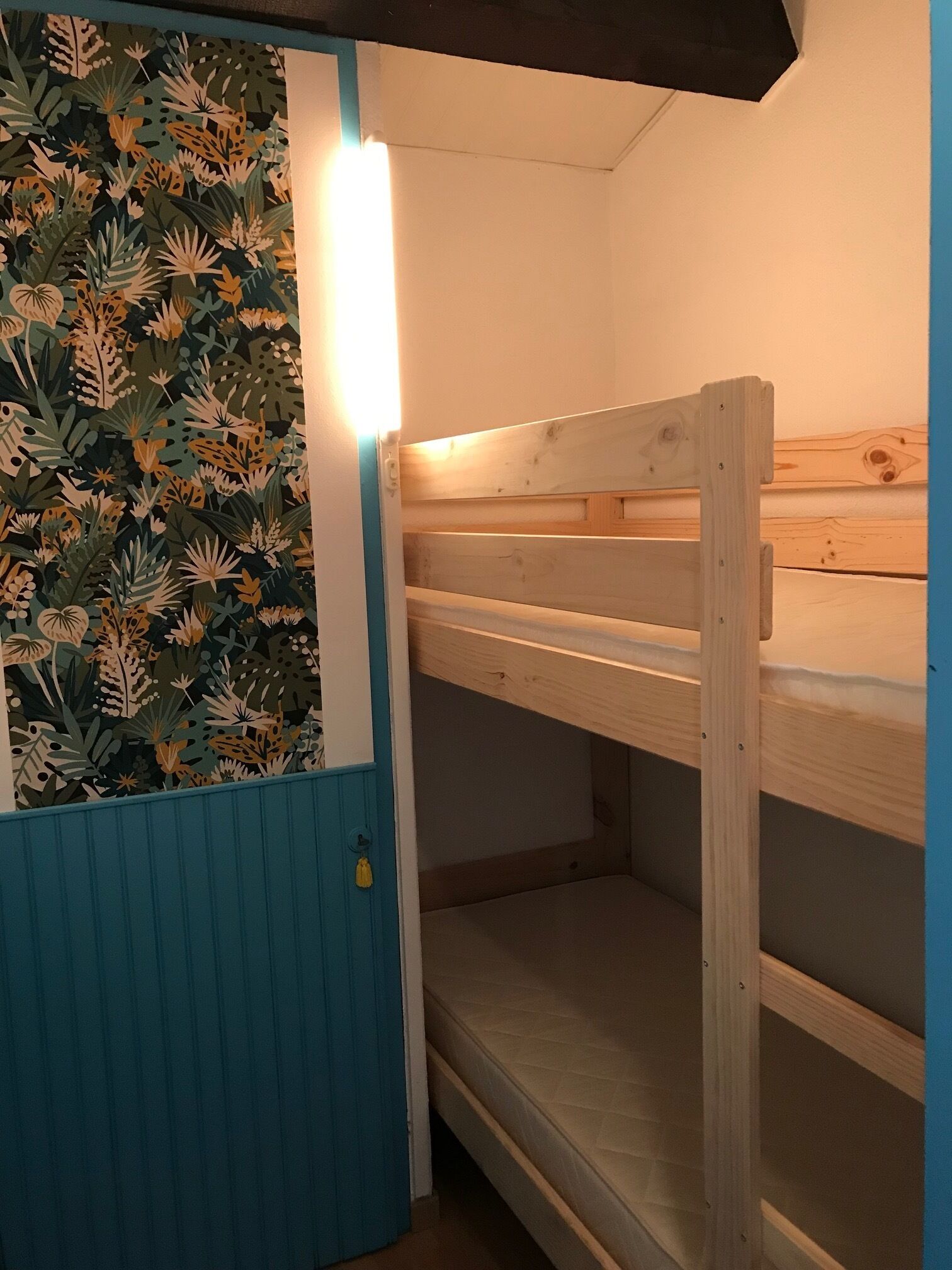 A bunk bed room with a blue door and a wall with a leaf pattern.