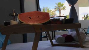 A room with a bed, a wooden table, a watermelon on the table, and a book on the floor. - Minimal Resort & Pool in Siviri, 150m From the Sea (Kassandra)