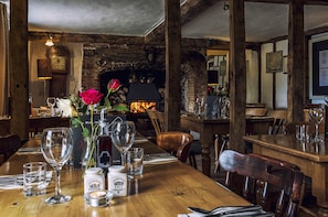 A rustic dining area with wooden tables, chairs, and a brick wall.