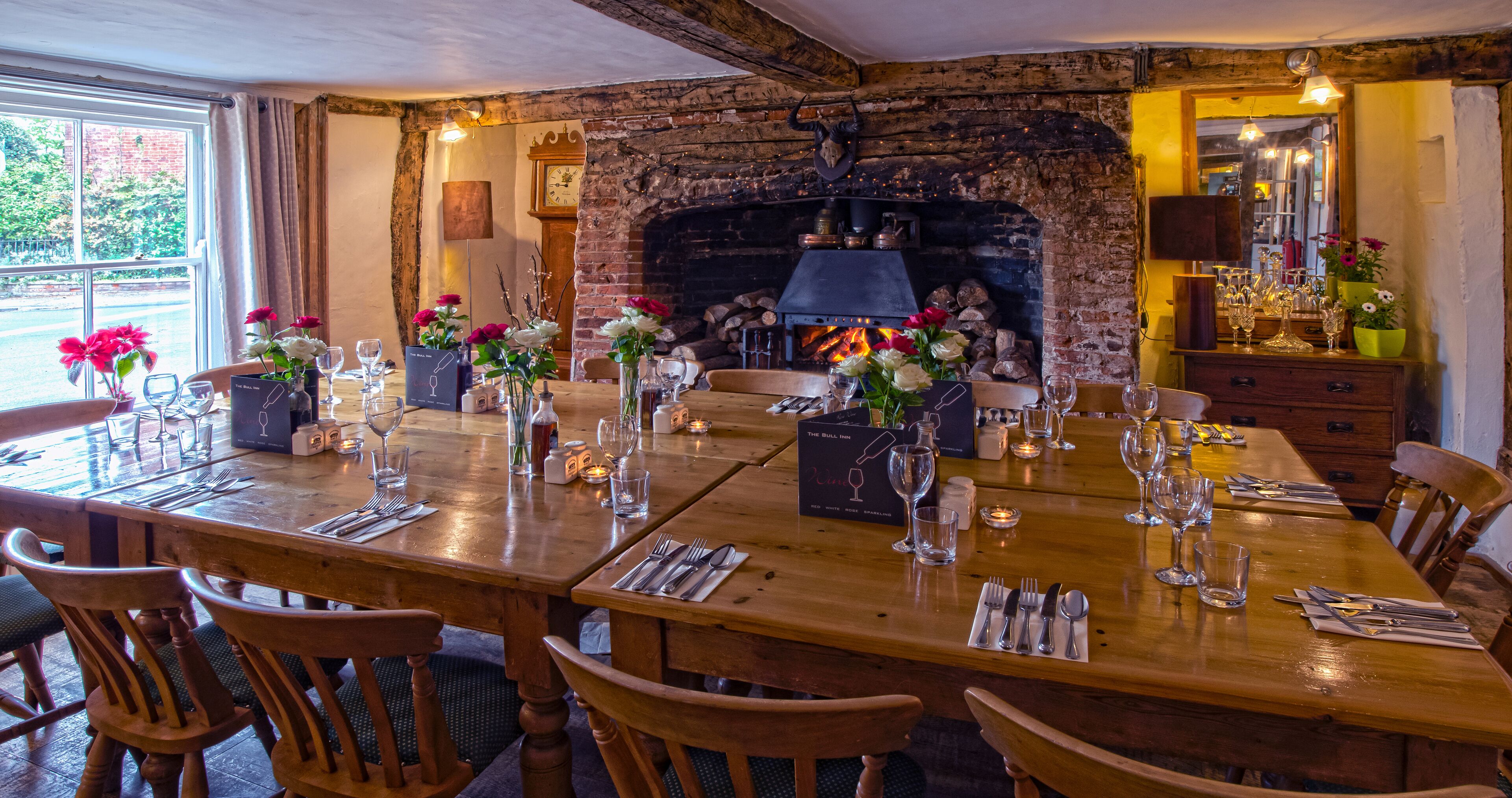 A dining area with a brick fireplace, wooden tables, and chairs.
