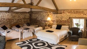 A rustic room with two single beds, a sofa, a chair, and a television. - The Litcham Bull Inn (King's Lynn)