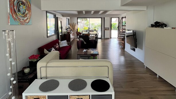 Een ruime woonkamer met een moderne bank, een bijzettafeltje en een decoratief wandobject.