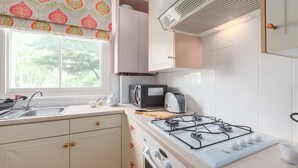 Eine Küche mit Gasherd, Mikrowelle, Toaster und einem Fenster mit Blick auf Bäume.