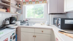 Eine moderne Küche mit Fenster, Wasserkocher, Kaffeemaschine, Mikrowelle und Spüle.