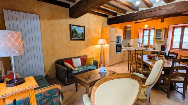A cozy living room with a sofa, a coffee table, and a dining area with chairs and a table.
