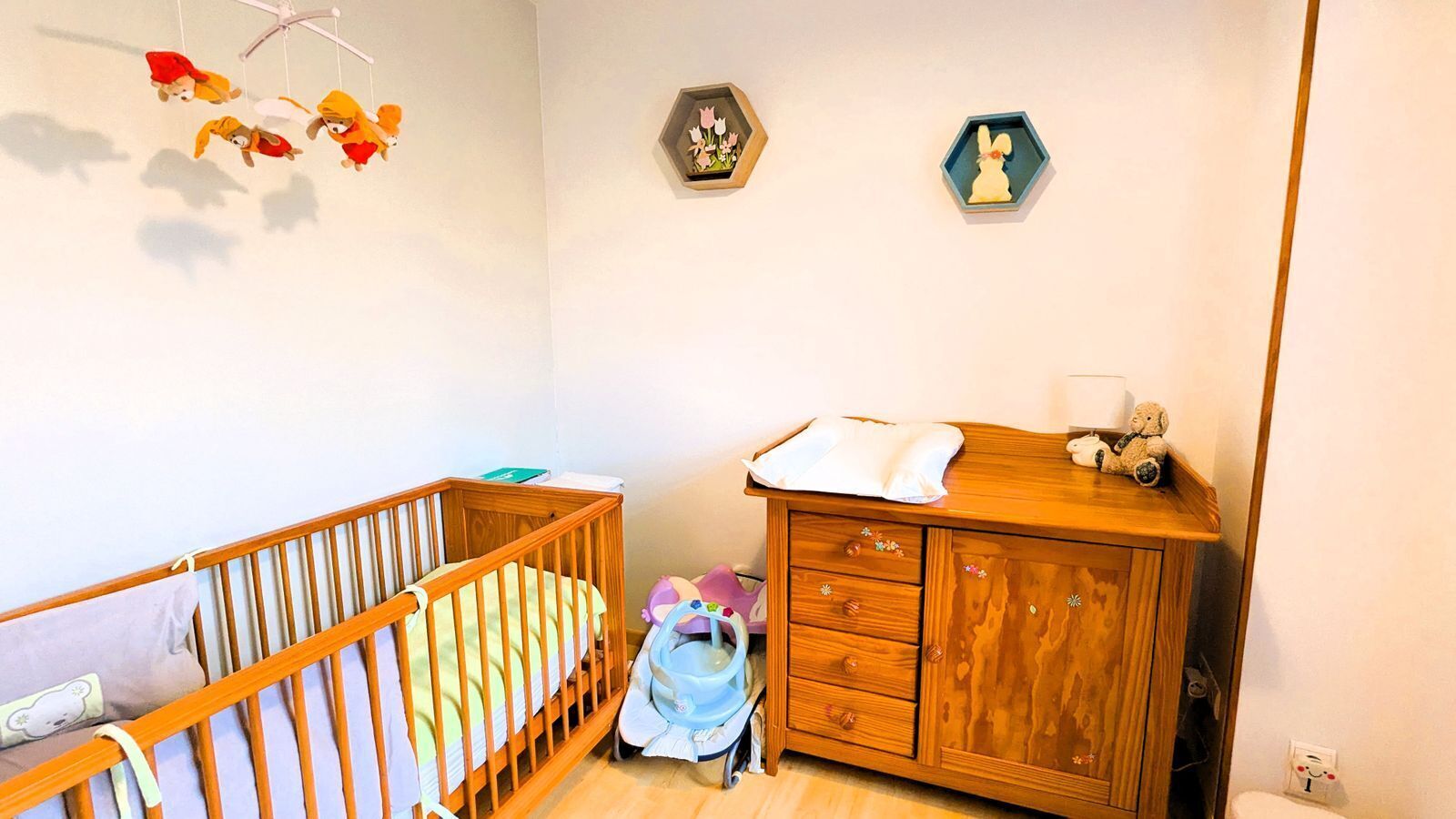 Una habitación infantil con una cuna, un cambiador y un armario de madera.