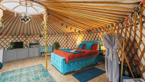 Ein gemütliches Zimmer mit einem Bett, einem Kleiderschrank, einem Schreibtisch und einem an der Wand hängenden Bademantel.