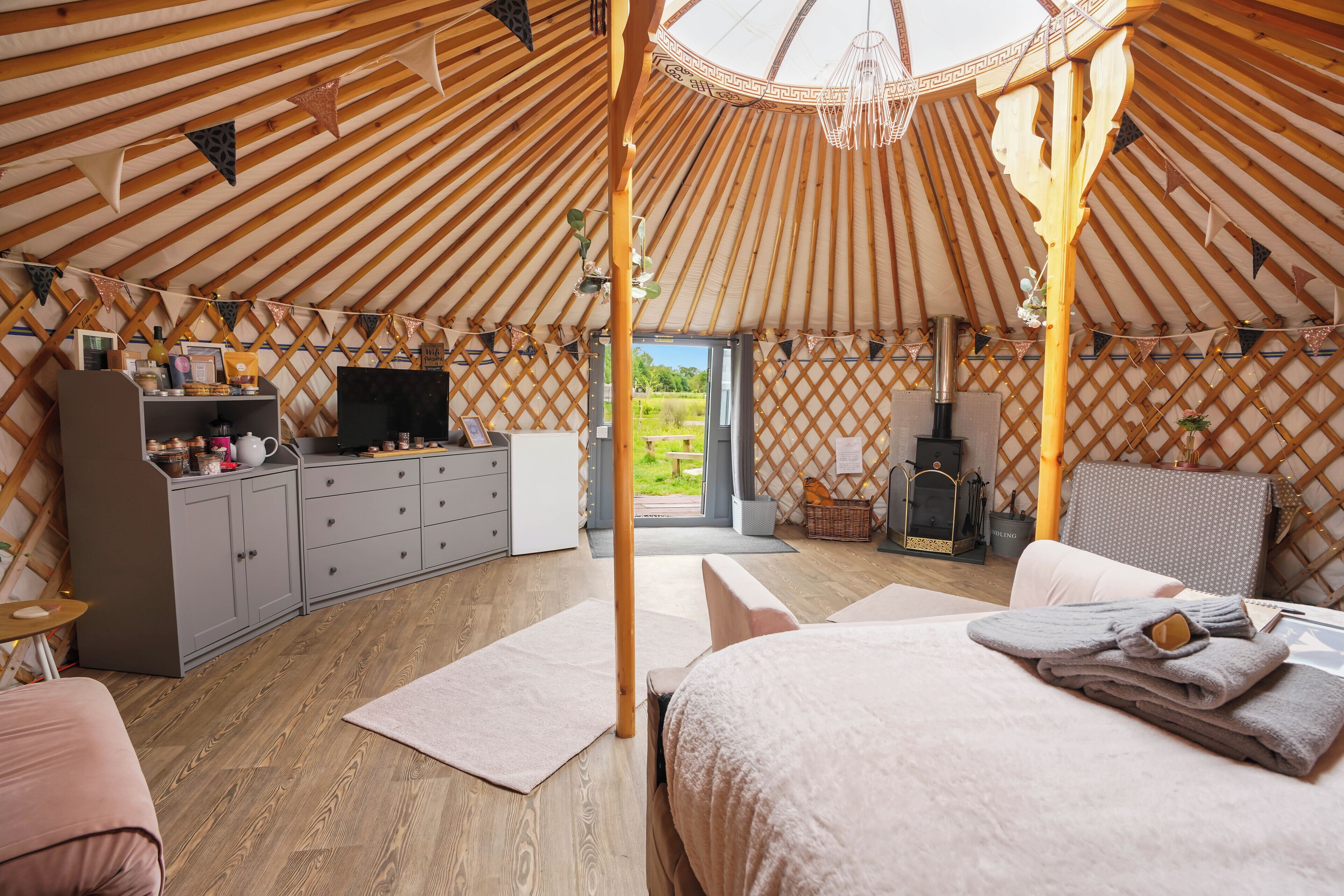 Interieur van een joert met een bed, zithoek, keuken en een televisie.