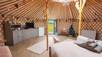 Interieur van een joert met een bed, zithoek, keuken en een televisie.