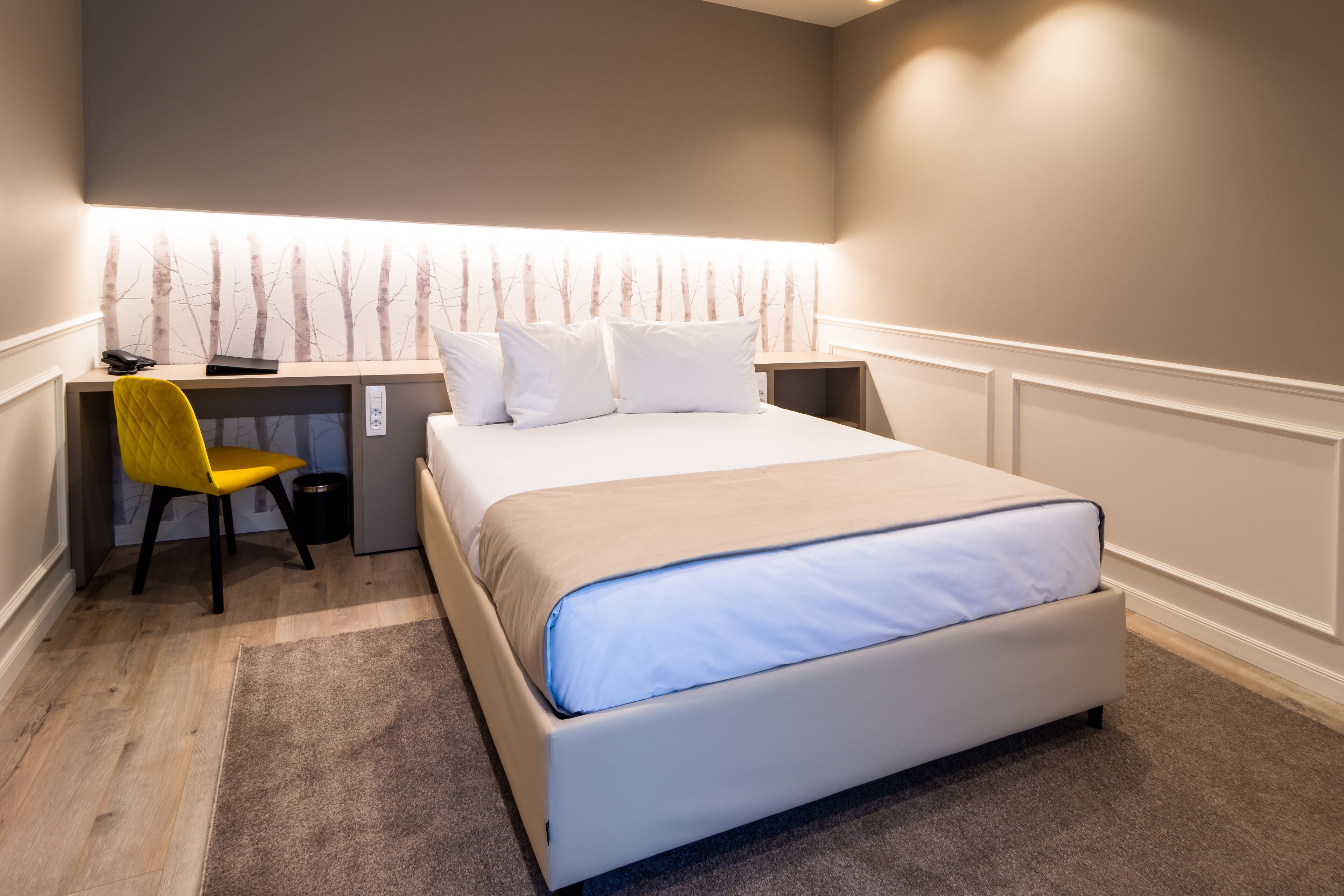 A bedroom with a bed, a desk, and a chair.