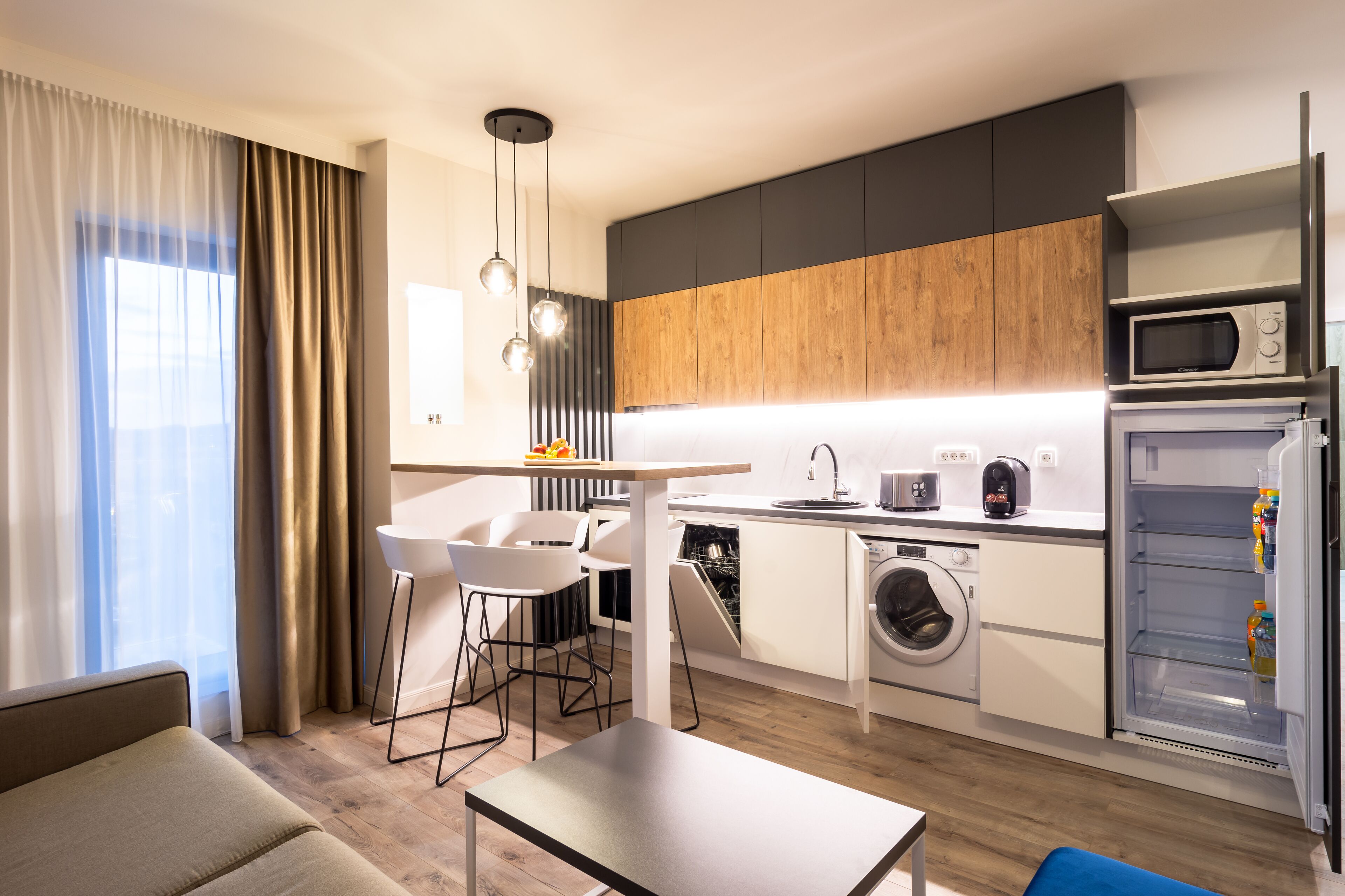 Une cuisine moderne équipée d’un lave-linge, d’un four à micro-ondes et d’un coin repas avec une table et des chaises.