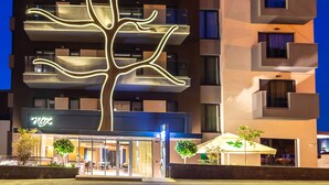 A modern building with a unique tree-like facade design, multiple balconies, and a visible entrance with a sign. - Aparthotel NOX (Cluj-Napoca)