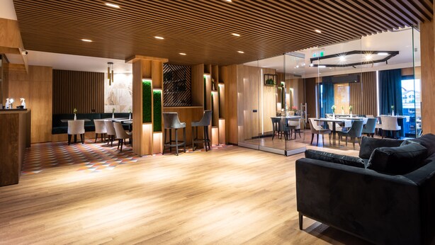 A modern interior with a wooden ceiling, a dining area, and a seating area with a sofa. - Aparthotel NOX (Cluj-Napoca)