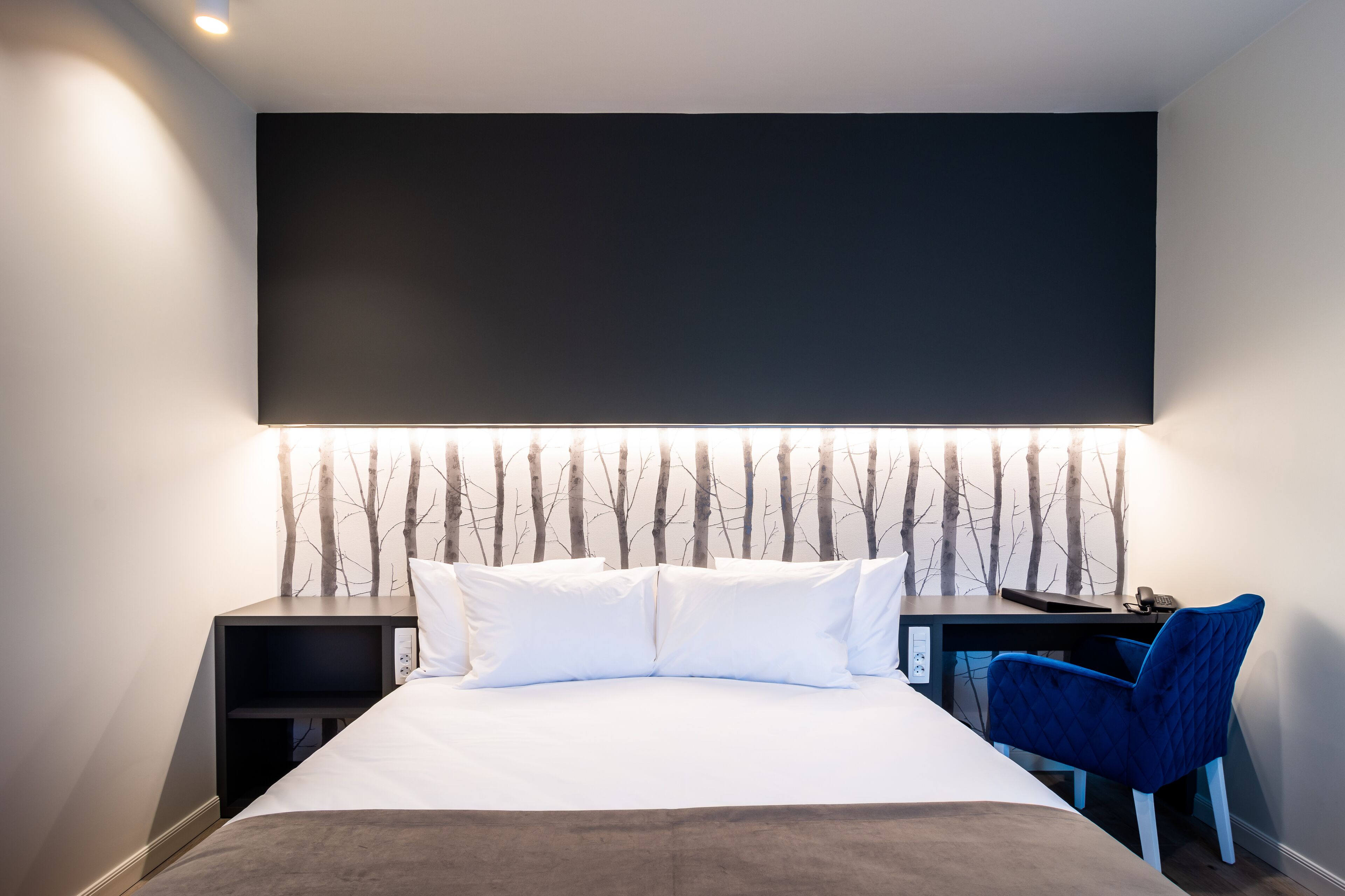 Una habitación de hotel moderna con una cama grande, un escritorio y una silla.