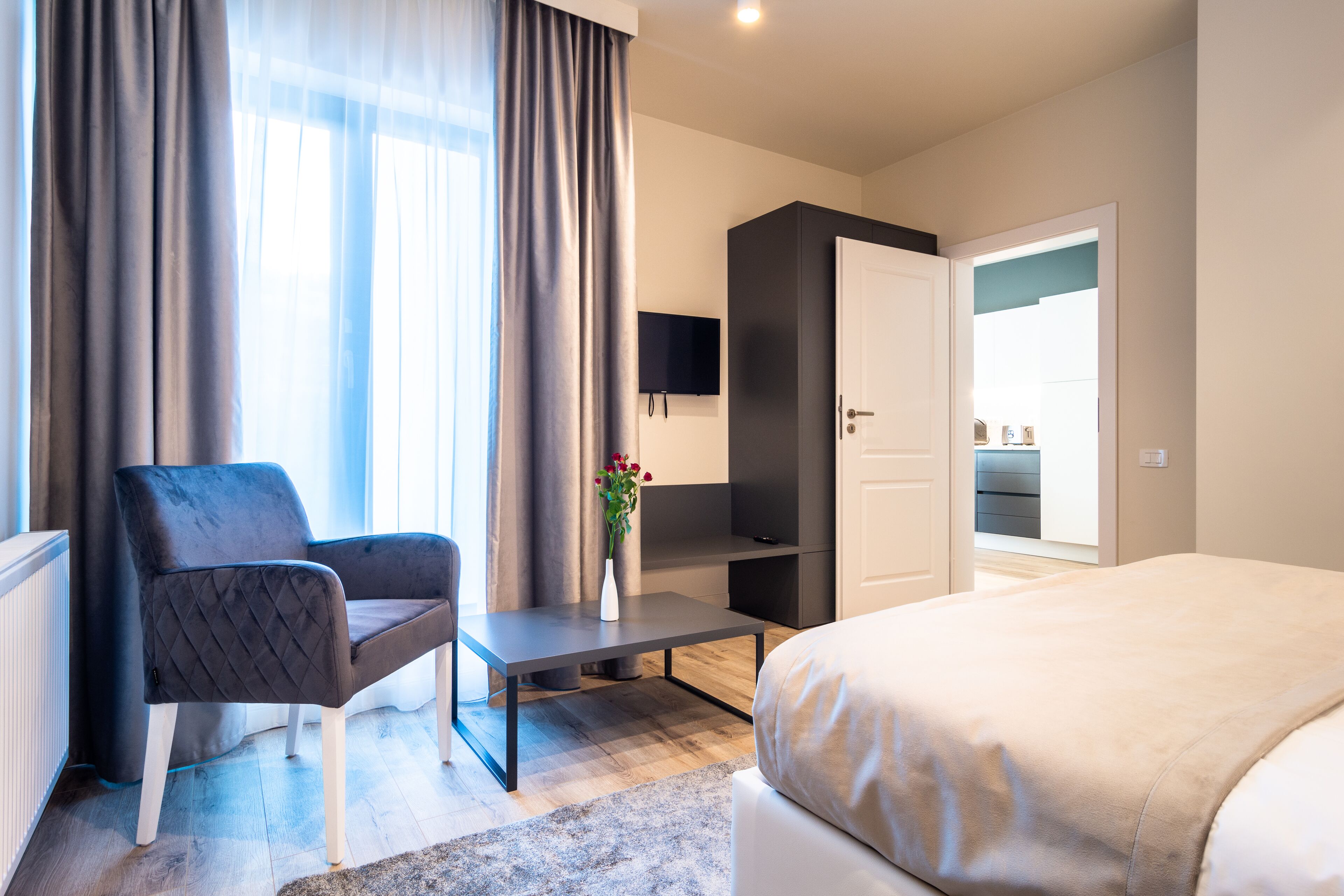 Una habitación de hotel moderna con cama, escritorio, silla, televisión y vistas al exterior.