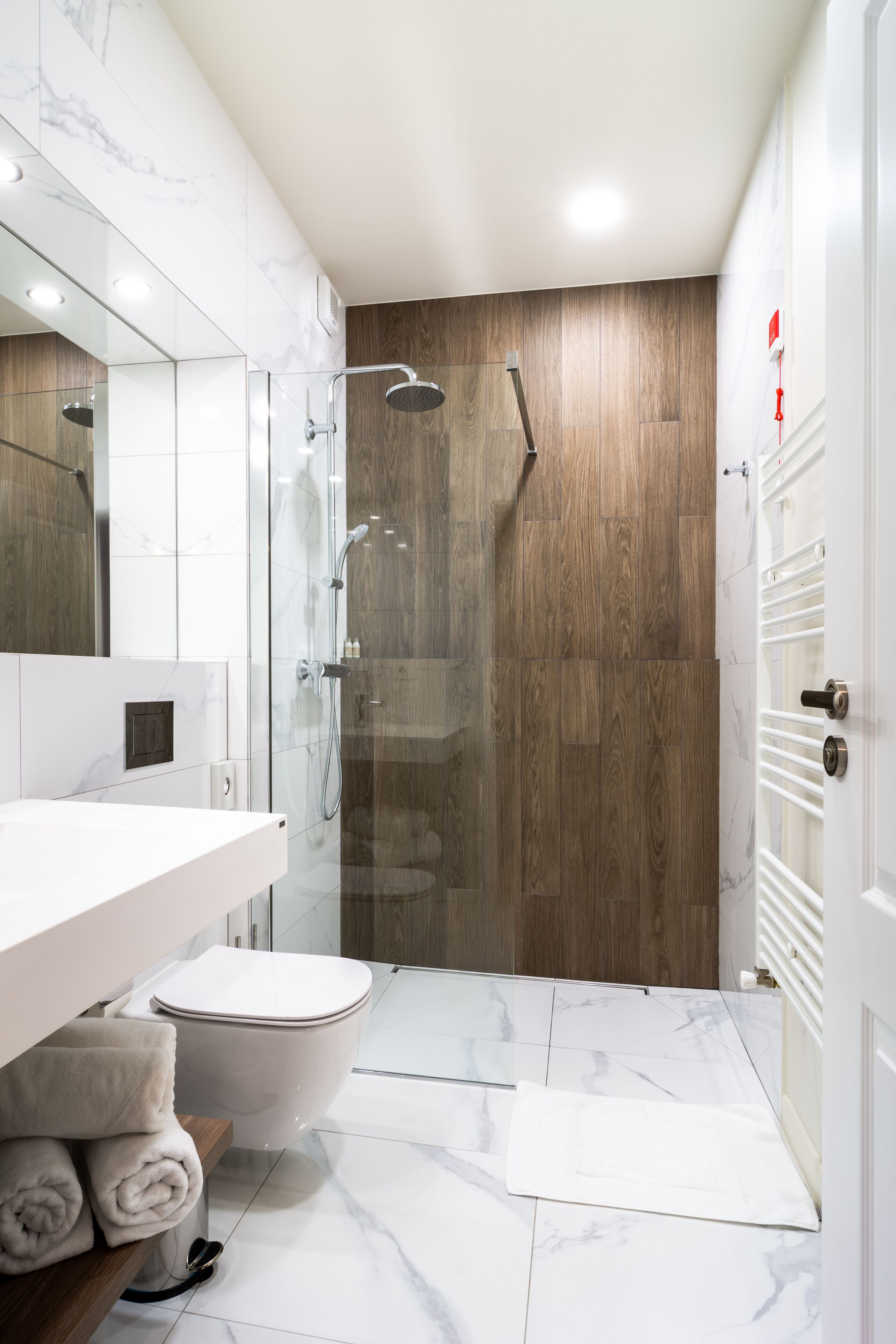 A modern bathroom with a glass-enclosed shower, a white sink, and a toilet.