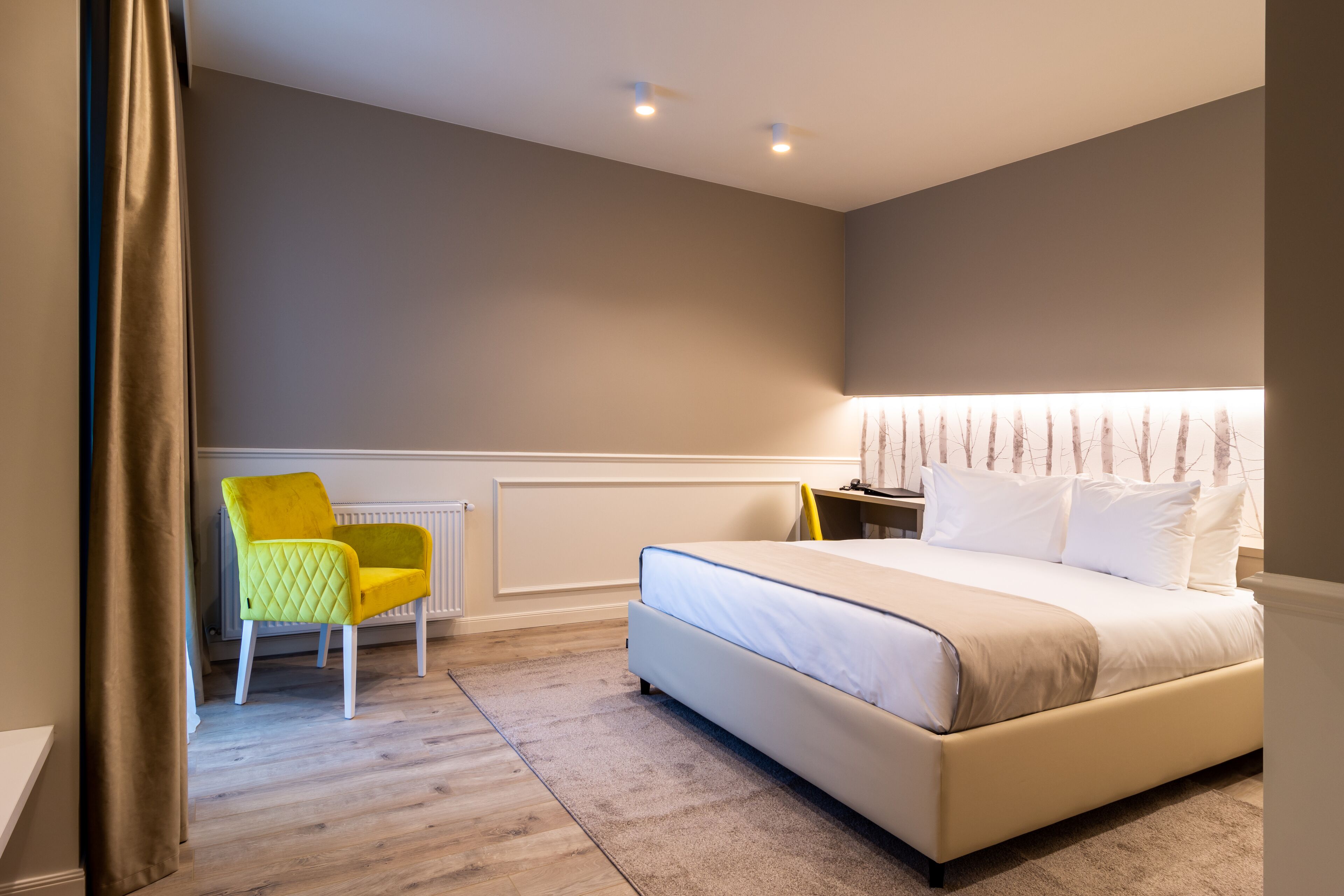 A bedroom with a bed, a nightstand, a chair, and a radiator.