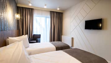 Une chambre d’hôtel avec deux lits, un téléviseur fixé au mur et une vue sur l’extérieur par la fenêtre.