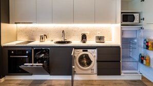 A compact kitchen with built-in appliances including a dishwasher, washing machine, microwave, and a coffee maker. - Aparthotel NOX (Cluj-Napoca)