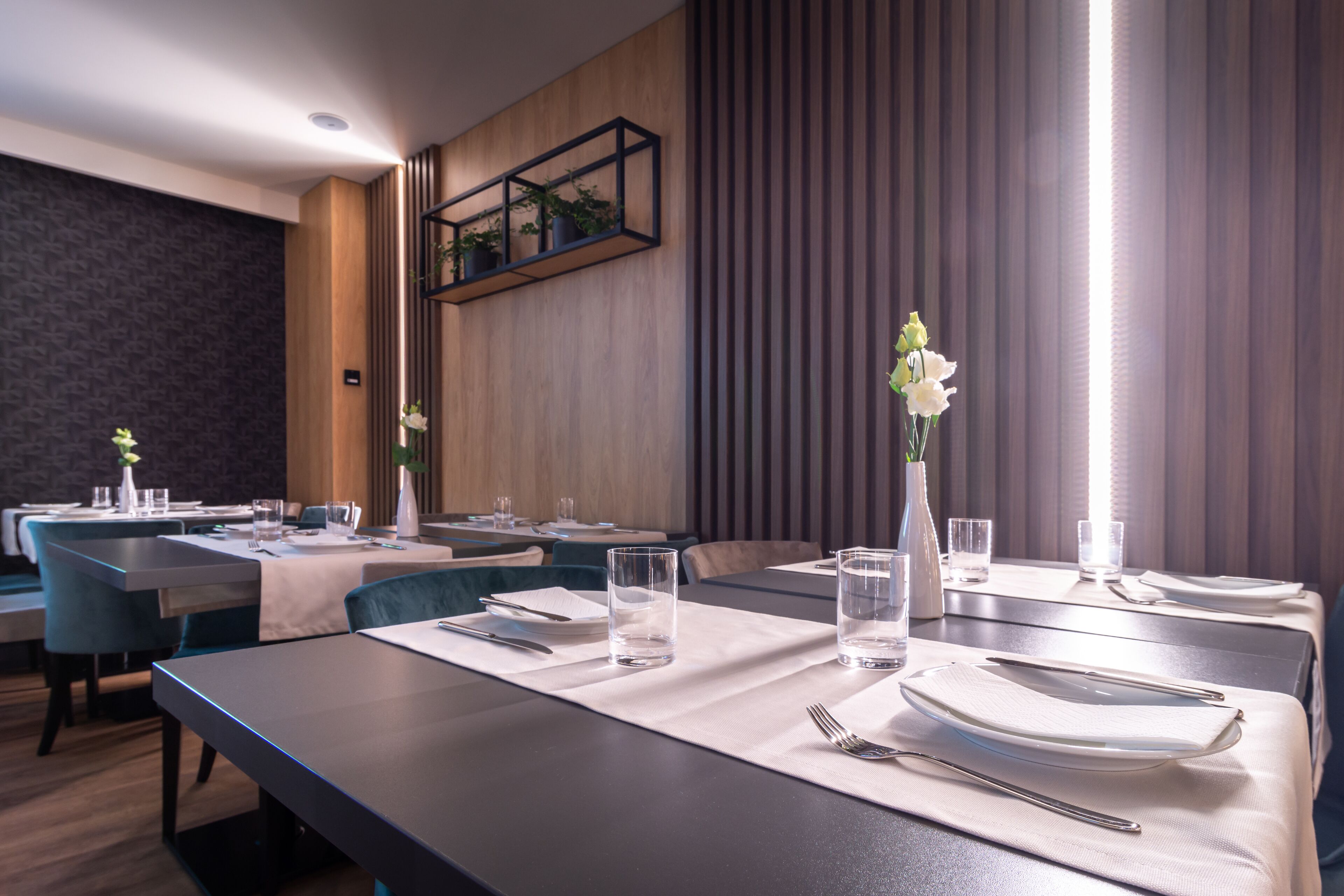 A modern dining area with multiple tables, each set with plates, cutlery, and glasses.