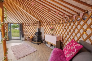 A cozy interior with a wooden ceiling, a fireplace, a sofa, and a small table.