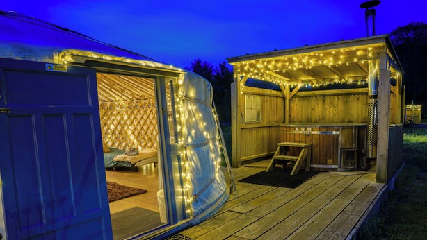Eine Holzterrasse mit überdachter Sitzecke und kleiner Outdoor-Küche.