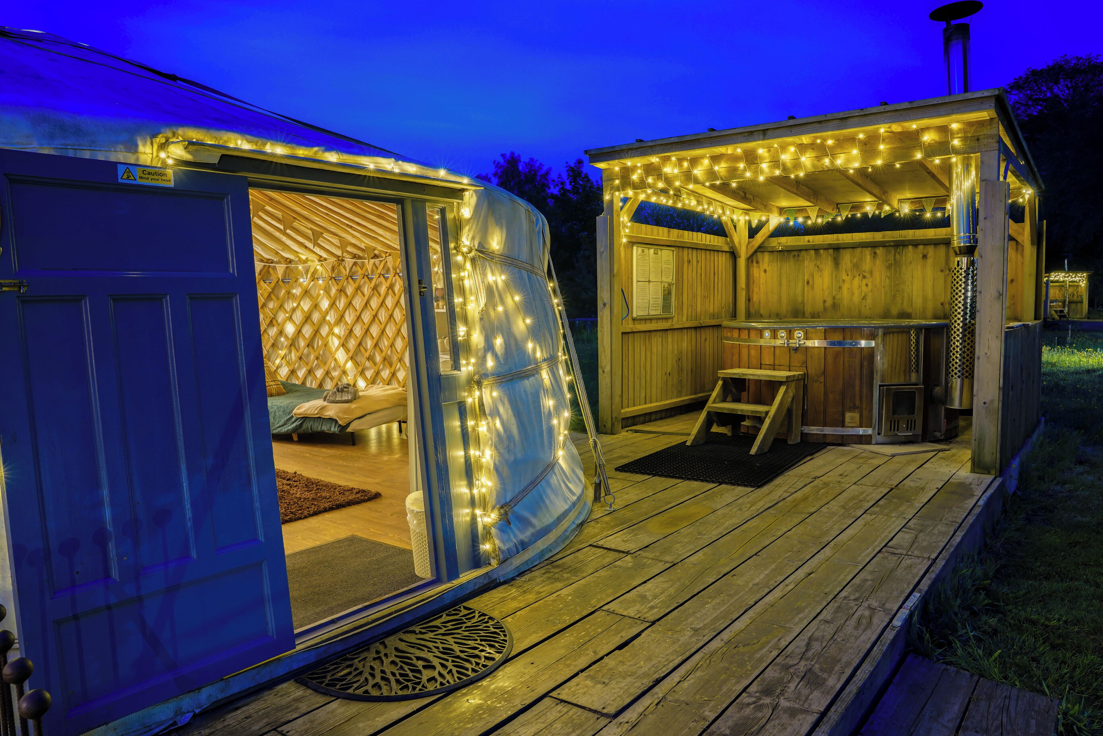 Een houten terras met een overdekte zithoek en een kleine buitenkeuken.