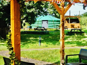 A wooden pergola with a picnic table and a bench, a green tent in the background, and a wooden structure with a bench. - TAITTINGER Luxury Heated Yurt with Private Hot Tub (Great Ellingham)