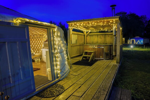 A wooden deck with string lights, a covered outdoor seating area, and a visible door.
