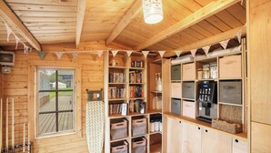 Eine Holzjagdhuette mit eingebautem Bücherregal, Stauräumen und einer Küchenzeile.
