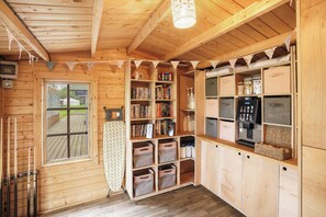A wooden cabin with a built-in bookshelf, storage bins, and a kitchenette.