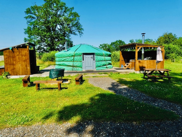 A yurt with a door, a wooden structure with a bench, and a picnic table. - TAITTINGER Luxury Heated Yurt with Private Hot Tub (Great Ellingham)