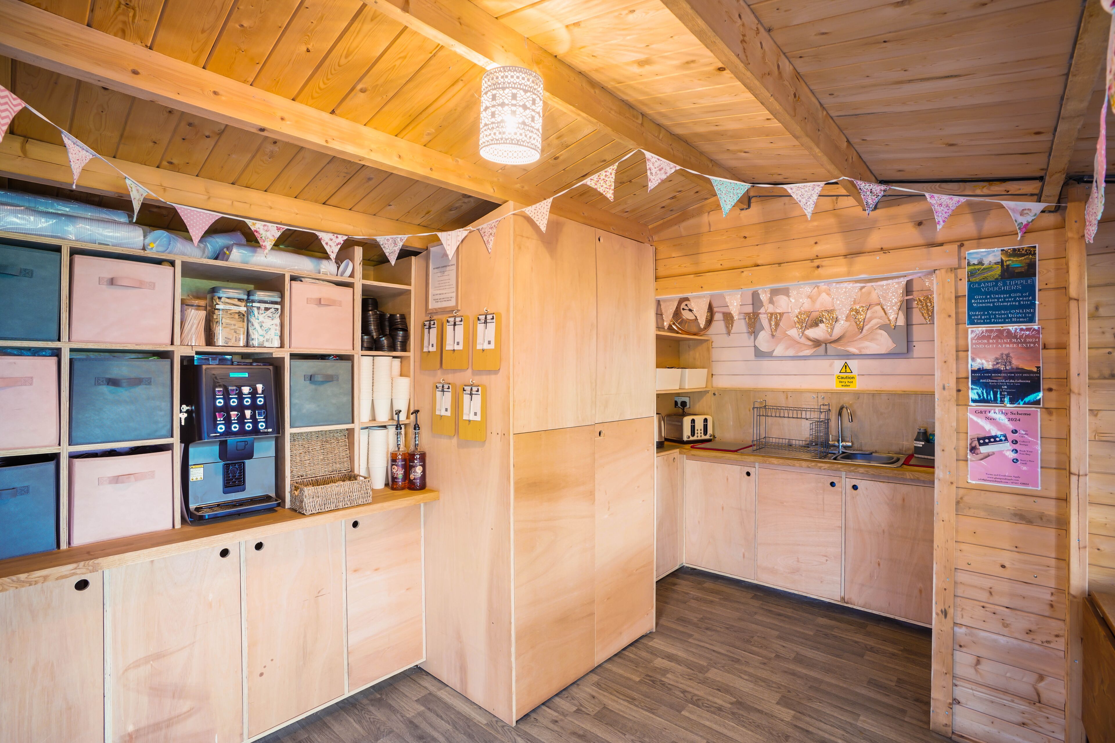 Interior em madeira com armários, máquina de café e cozinha equipada com pia e utensílios.
