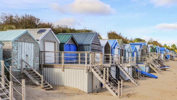 Una hilera de cabañas de playa con escaleras de madera que dan a cada una.
