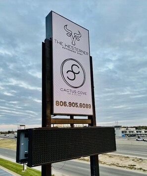 Un cartel publicitario de The West Ender Extended Stay Cactus Cove Inn & Suites, con el número de contacto 806.905.6089.