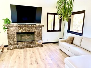 TV connectée, cheminée, livres, chaîne hi-fi