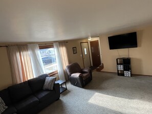A living room with a sofa, a recliner, a TV, and a storage unit.