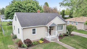 A single-story house with a front porch, a small garden, and a clear sky.