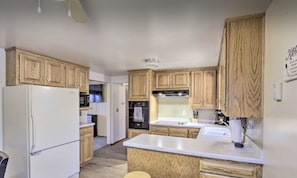 Una cocina compacta con gabinetes de madera, un refrigerador blanco, un microondas, una estufa y un fregadero.