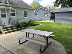 A picnic table in a backyard with a house in the background.