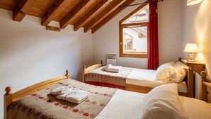 A bedroom with two beds, wooden beams, a window with red curtains, and a nightstand with a lamp. - Duplex 4 rooms, 8 max, pets allowed, balcony (Valloire)
