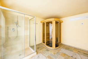 A bathroom with a glass-enclosed shower, a wooden bathtub, and a stone-tiled floor. - Pool Villa Angela Whirlpool (Manciano)