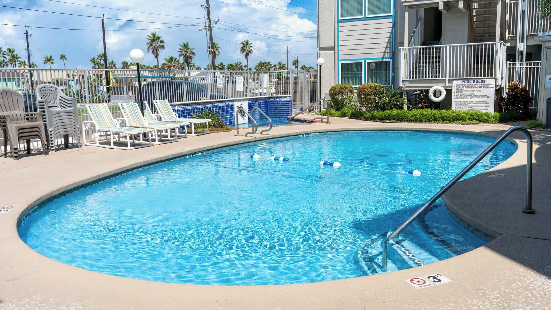 A swimming pool with lounge chairs and a fence.