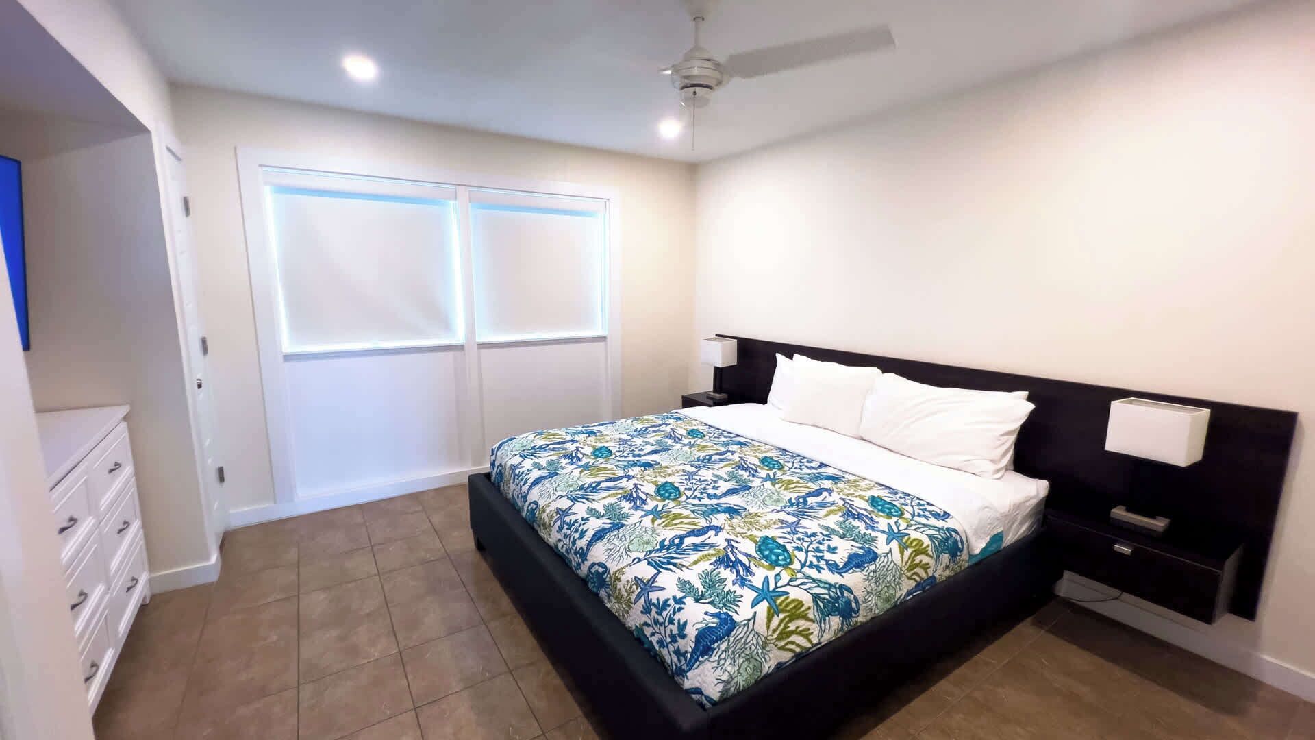 A bedroom with a bed, a nightstand, a dresser, and a ceiling fan.