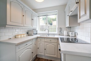 A modern kitchen with white cabinetry, a built-in oven, and a window with a view of the outside. - Stylish & Comfortable 3BR Spacious Home w/ Parking (Sheffield)