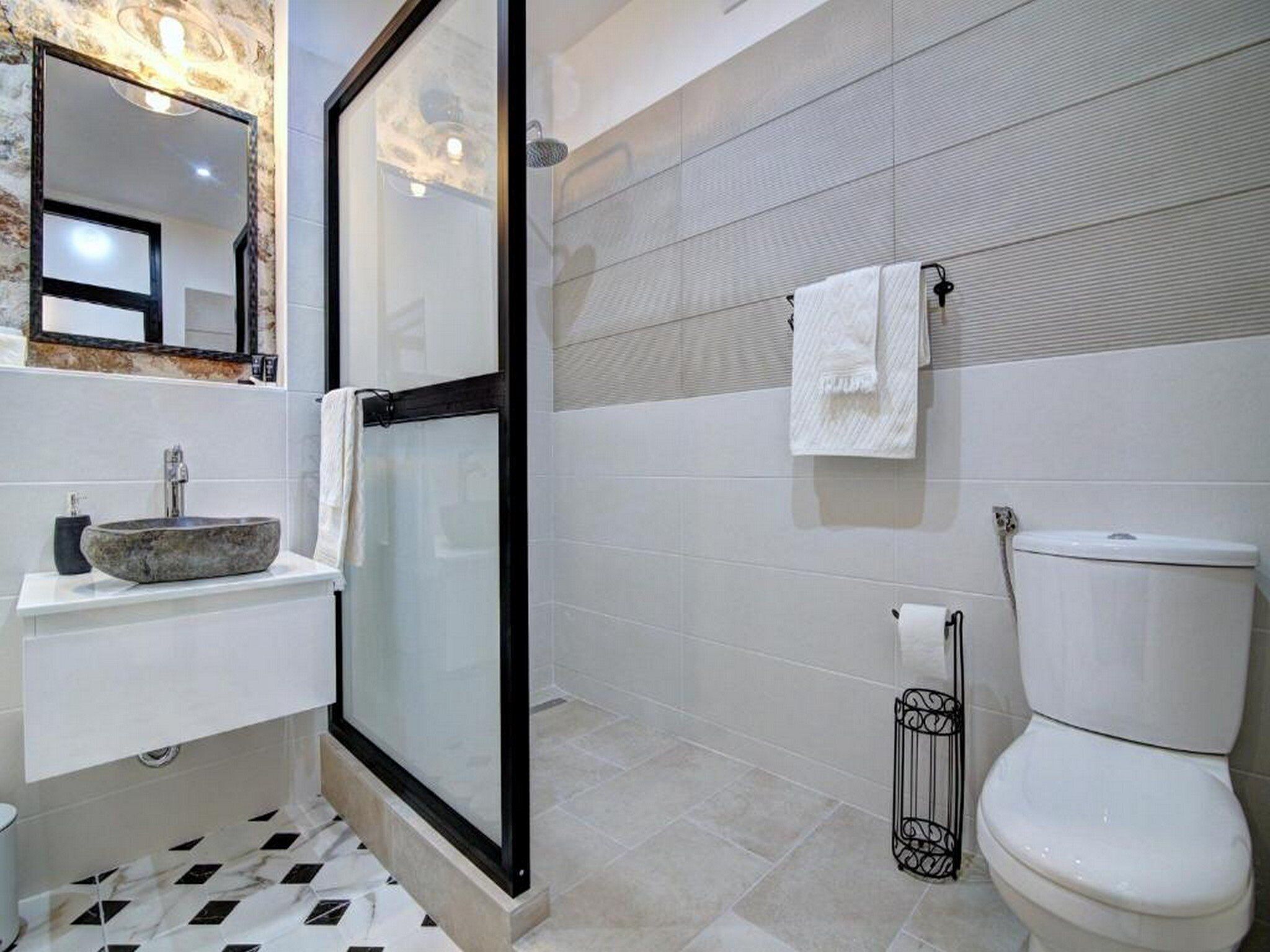 A modern bathroom with a glass shower enclosure, a white sink, and a toilet.