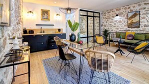 Una cocina moderna con zona de comedor, paredes de piedra y un ventanal grande.
