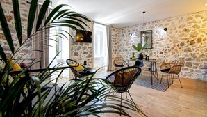 Amplia sala de estar con una pared de piedra, una mesa de comedor con sillas y una planta grande al frente.